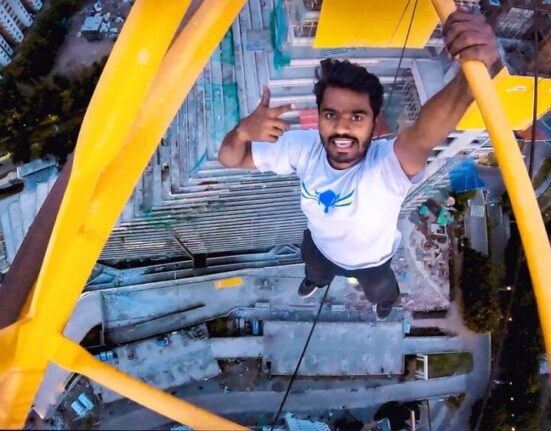 FIRST-PERSON TO HANG WITH ONE HAND ON BUILDING CRANE AT MAXIMUM HEIGHT